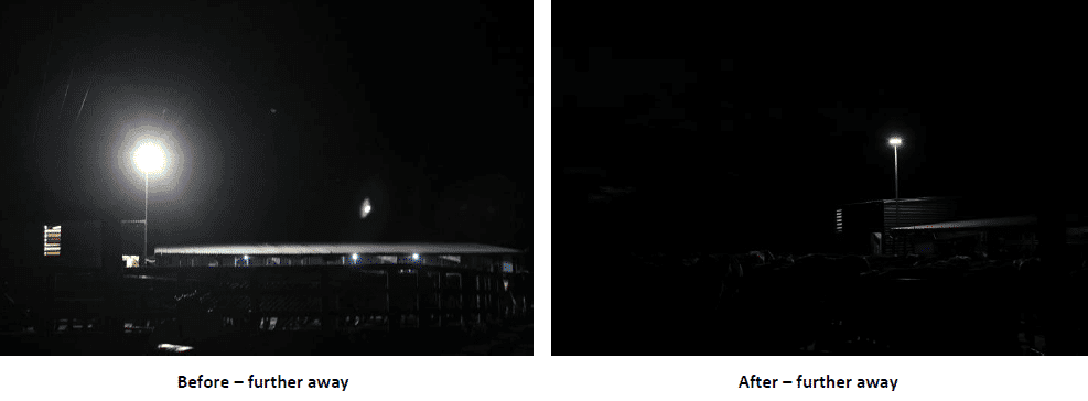 Nighttime scene with a bright streetlight over a fenced area and distant building (left); a smaller pole light over a dark area on the right.